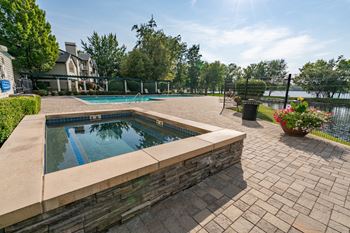 A pool surrounded by a stone wall and a paved area.
